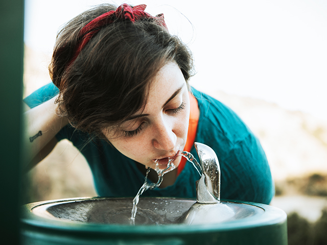 Woman drinking water from a water fountain